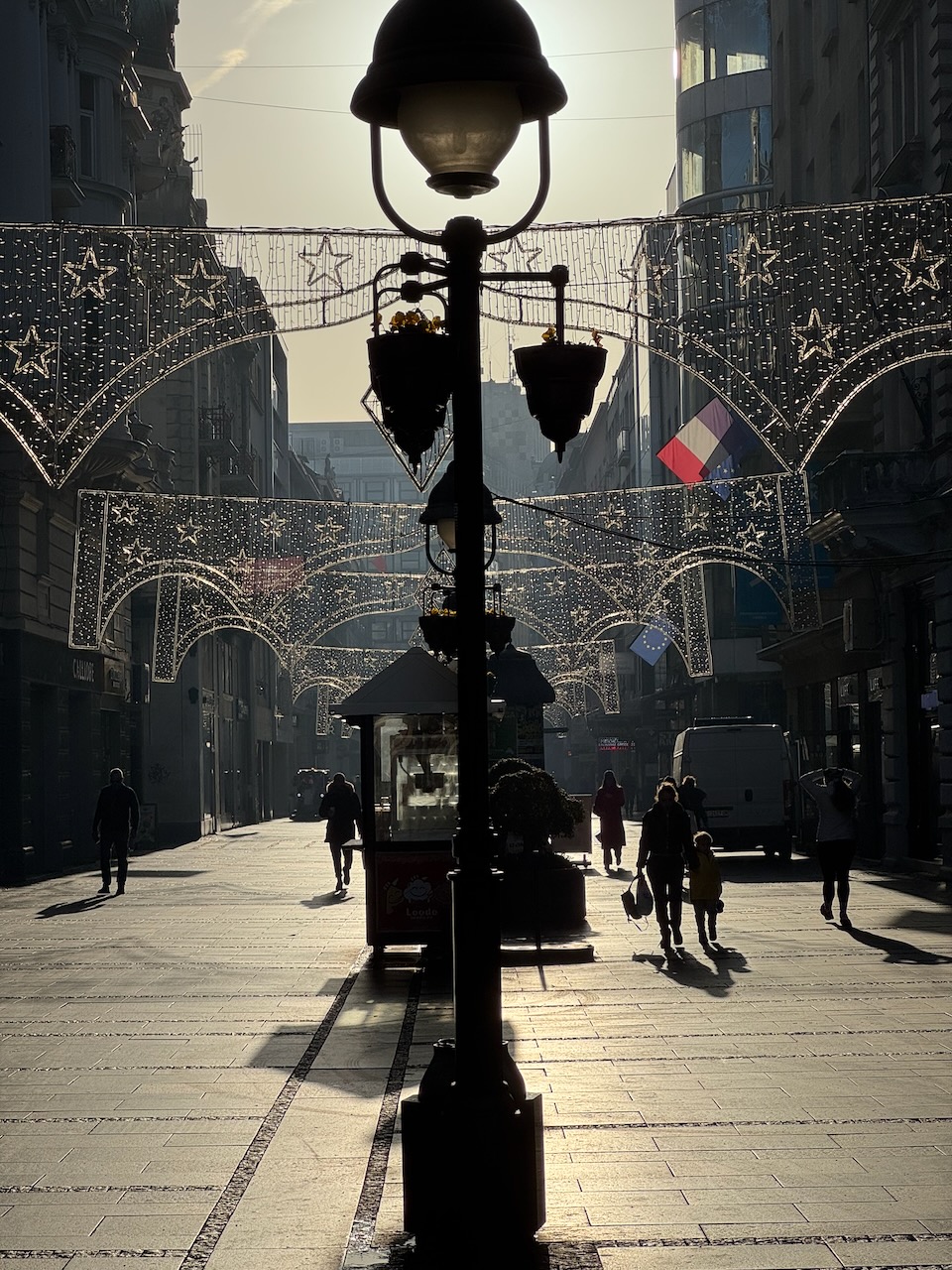 A street lamp beneath decorative lights in a city street
