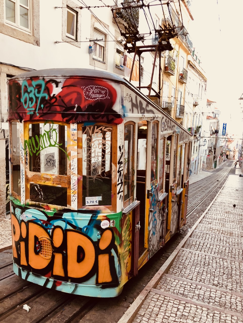 A graffiti-covered yellow tram on a steep street